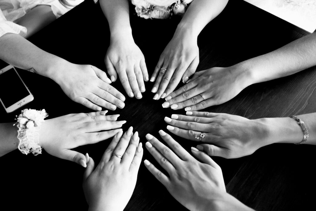 Black and white photo of female hands forming a circle on a table, symbolizing unity and friendship.