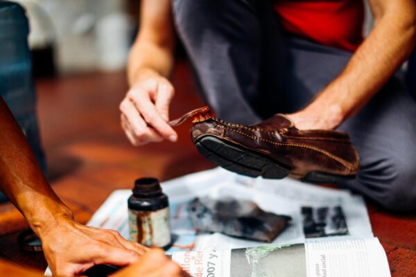 Close-up of hands skillfully polishing a leather shoe, showcasing craftsmanship and care.